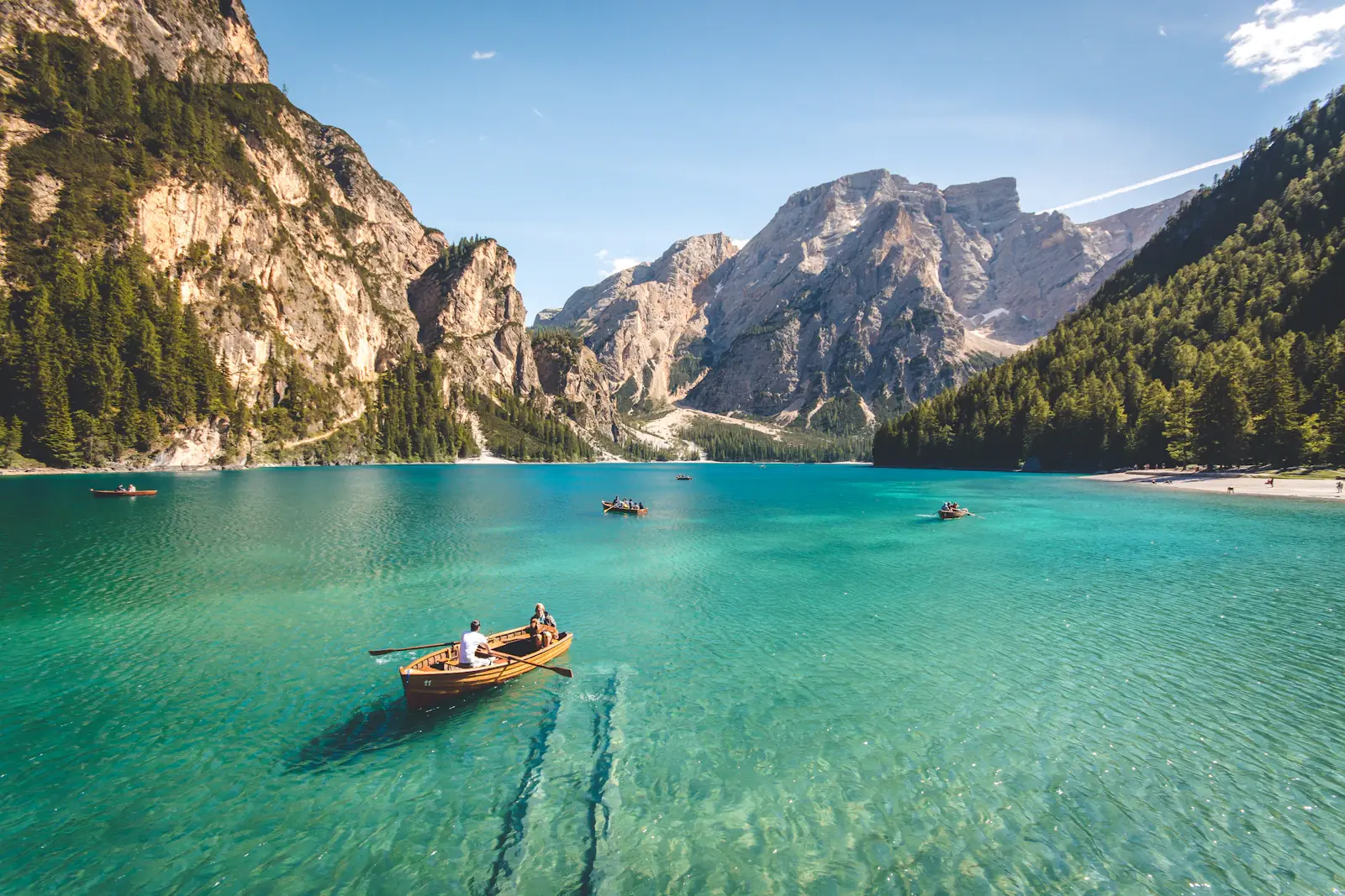 Small boats on a turquoise lake beneath steep mountains