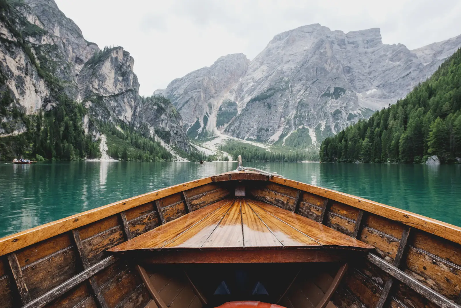 A wooden boat on a still lake below the Dolomites